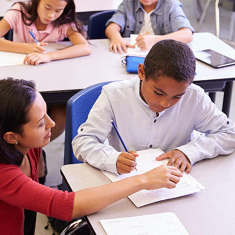 teacher coaching a student in a classroom