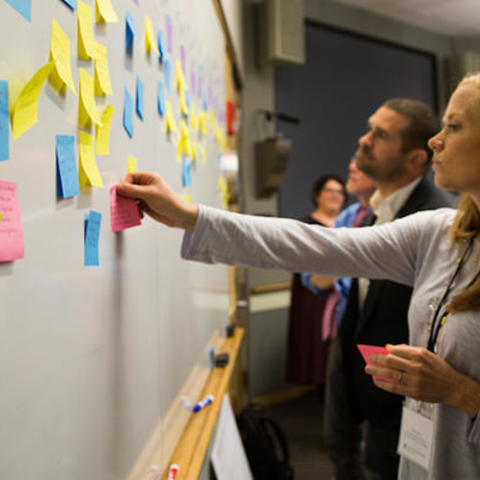 Woman adding a sticky note to a wall