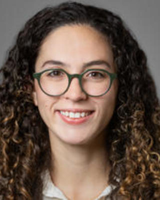 A woman with glasses and curly brown hair.