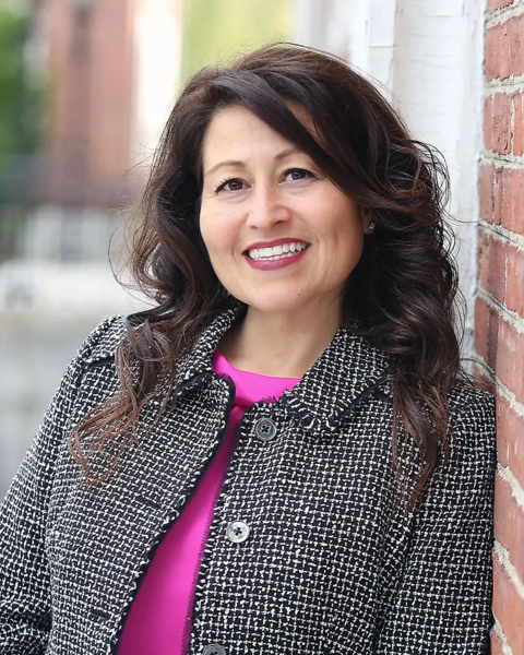 Adriana Umaña-Taylor wearing a pink blouse and checkered jacket